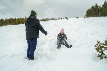 Playful couple having snowball fight in winter landscape