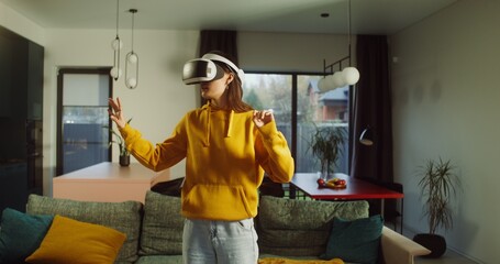 Woman wearing virtual reality glasses playing video game at home