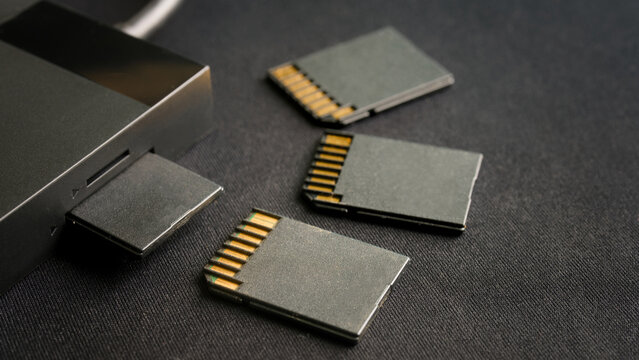 Professional photographer&rsquo;s workflow equipment. A card reader and several flash memory cards for backing up files on a dark textured background. Photo