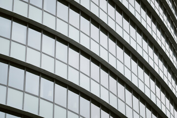 Modern urban architecture facade features curved glass windows on a building with grid pattern and reflection and sweeping lines