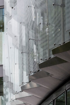Modern urban architecture facade shows glass windows on a building with grid pattern and reflection at entrance canopy detail