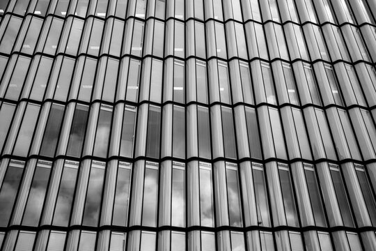 Modern urban architecture facade detail shows glass windows on a building with grid pattern and reflection plus diagonal cladding texture