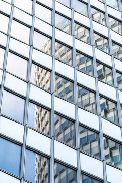 Modern urban architecture facade of glass windows on a building with grid pattern and reflection seen in strong upward perspective