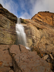 Obraz premium Waterfall coming over the cliff on Hastings beach from Ecclesbourne Glen east Sussex south east England UK