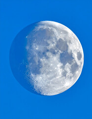 Detailed Moon Phase in Blue Sky Showing Craters and Lunar Surface
