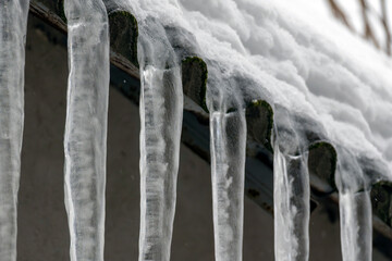 Icicles form on the edge of a roof during winter weather in a residential area
