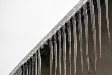 Icicles hanging from the edge of a roof during winter weather in a cold climate