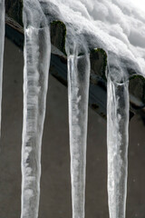 Icicles hanging from the edge of a roof during winter in a cold location