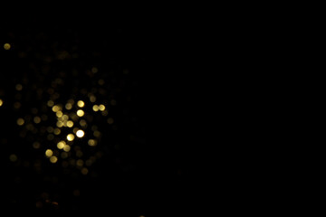 Golden blurred bokeh lights on black background. Glitter sparkle stars for celebrate. Overlay for your design