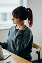 Woman Suffering from Shoulder Pain While Working on Laptop in Home Office