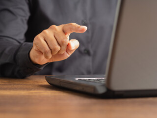 Business hand pointing at laptop screen on desk.