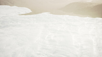 Obraz premium A breathtaking scene captures a vast glacier shimmering softly in the early morning light. The smooth surface contrasts with the distant rugged mountains, creating a serene atmosphere.