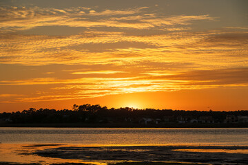 Warm orange sunset sky above lagoon and distant tree line in Furadouro Portugal, Ovar &ndash; Furadouro, 12 November 2025