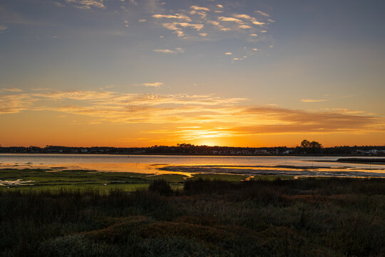 Layered sunset clouds glowing above calm lagoon landscape in Furadouro Portugal, Ovar &ndash; Furadouro, 12 November 2025