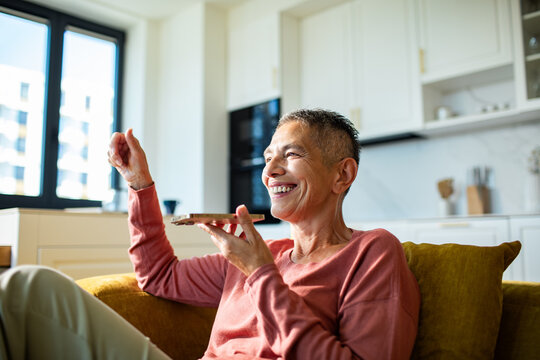 Smiling senior woman using voice assistant at home