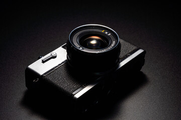 暗い背景にスポットライトが当たった古いフィルムカメラ