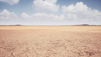 A wide expanse of cracked earth stretches into the horizon, with a backdrop of fluffy white clouds against a bright blue sky. Distant hills hint at natures beauty beyond.