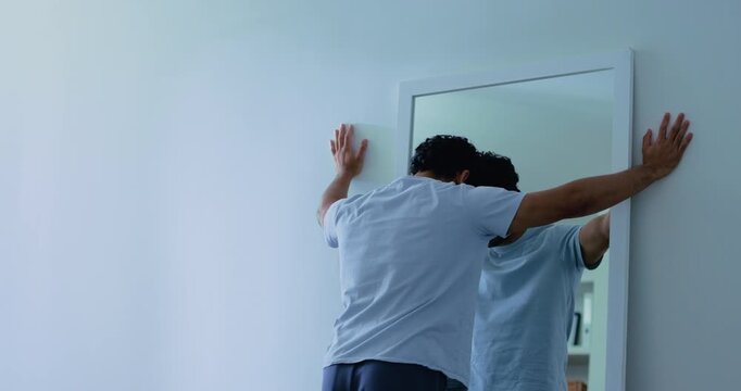 Mirror, mental health and man with sadness in home, disappointment and negative thoughts from back. Mockup space, bad self image and insecure person with depression for sorrow, reflection or hopeless