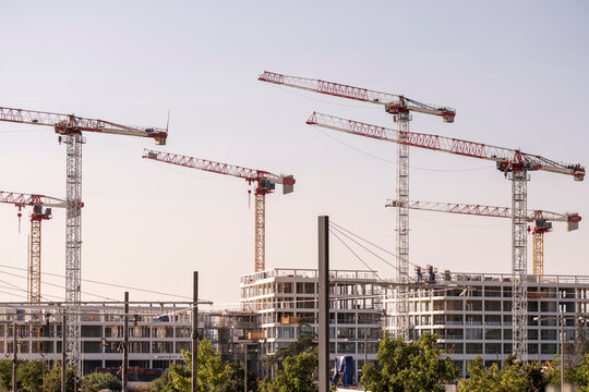 construction crane building architecture urban development property concrete scaffold montpellier France sunset glow behind tower crane over new skyline - Powered by Adobe