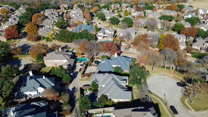 Coppell homes with gray and brown roofs arranged in a grid with cul-de-sacs; pools, fences, and vibrant autumn trees frame clean streets and manicured lawns in a quiet, suburbs Dallas, Texas