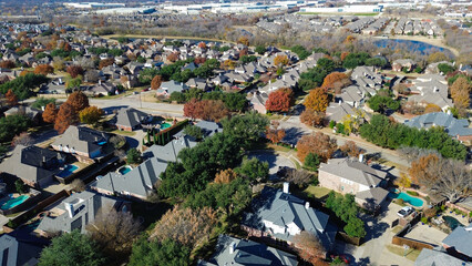 Coppell homes with pools and fall trees line curved streets and cul-de-sacs; white-roofed buildings and a pond in the distance highlight suburban-commercial juxtaposition, suburbs Dallas, Texas