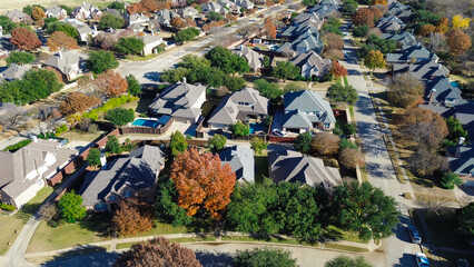 Grid-like Coppell neighborhood with fenced backyards, pools, and tree-lined streets; mix of green and autumn leaves adds seasonal texture to clean residential infrastructure, Texas
