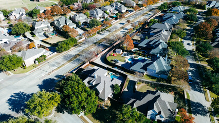 Coppell homes with pools and fenced yards line wide, clean streets with sidewalks and streetlights; fall foliage and mixed architecture add depth to the organized, suburbs Dallas, Texas