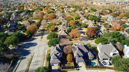 Grid-style Coppell neighborhood with fenced yards, driveways, pools, and vivid autumn foliage; single-family homes packed tightly along tree-lined streets with visible infrastructure, Texas