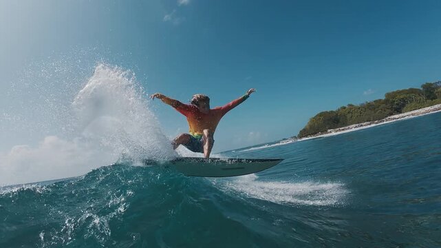 Teen boy surfer rides the wave in the ocean in the Maldives and does radical snap on the section