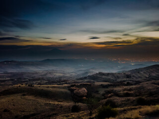 Sunset over a dry grassy field with distant mountain range under a clear gradient sky. High quality photo