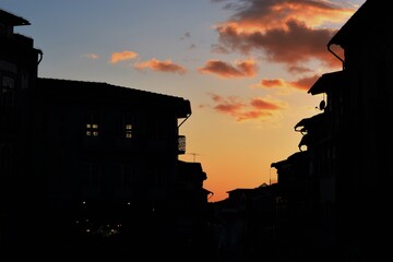 Obraz premium Silhouette of old city buildings against sunset sky with sparse clouds