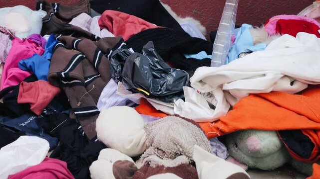 Overflowing trash bins with clothes, piles of unwanted clothes lying, clothing bins in the city, a company sort the clothes to be sold or recycled. High quality 4k footage