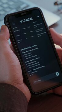 Close-up of a person using an AI chatbot app on their phone to generate business ideas. Virtual assistant with artificial intelligence helps with daily tasks. Conversation with AI application. 