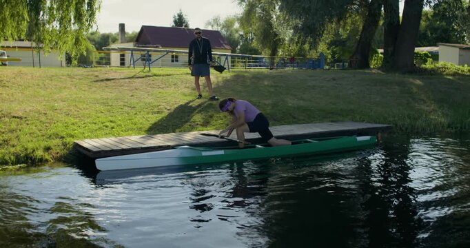 A female rower sets off from the pier in a canoe.