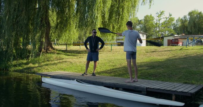 A guy practices rowing technique while standing on the pier, then gets into a kayak.