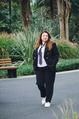 A beautiful middle-aged businesswoman in a business suit walks down the street. Vertical photo.