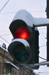 Snow covered street road traffic light with active red light.