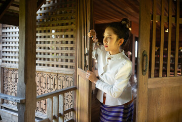 Beautiful young Asian woman in traditional Thai Lanna dress in an old house in Chiang Mai, Thailand.