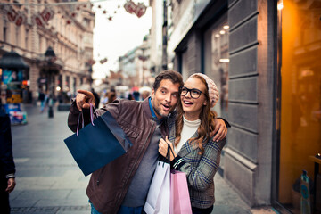 Smiling couple shopping on urban street in autumn
