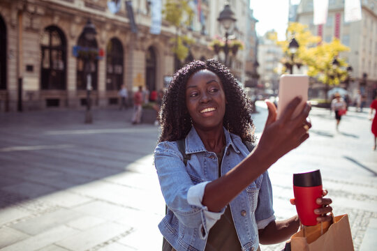Young woman taking selfie on sunny city street