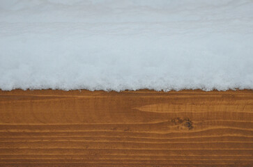 Snow covered brown -orange wooden board. Closeup outdoors photo. Winter ,snow covered backgrounds.