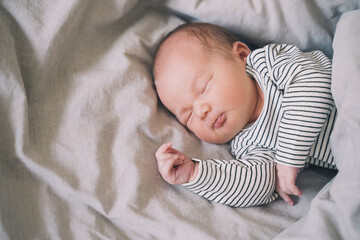 Newborn sleep at first days of life. Portrait of new born baby one week old in crib in cloth background.