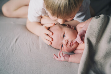 Siblings bonding. A boy and his little new born brother. Child and newborn baby at home. Concept of family with kids.