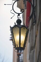  Yellow light glass lantern hanging  on exterior wall of the building against street sky background.. Closeup outdoors  photo.
