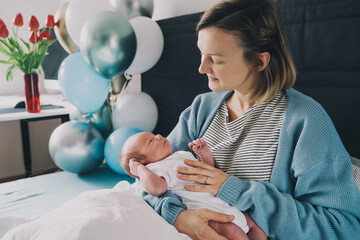 After baby delivery mother and baby at home. Mother holds her newborn in hands. Mom and baby together. Childbirth and motherhood concept. Family celebrates birth of baby boy.