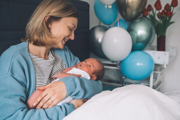 After baby delivery mother and baby at home. Mother holds her newborn in hands. Mom and baby together. Childbirth and motherhood concept. Family celebrates birth of baby boy.