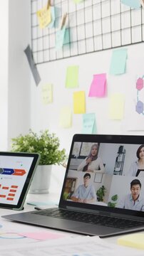 Vertical Screen : Asia businesspeople using laptop talk to colleagues discussing business brainstorm about plan in video call meeting in office. Lifestyle social distancing and work after coronavirus.
