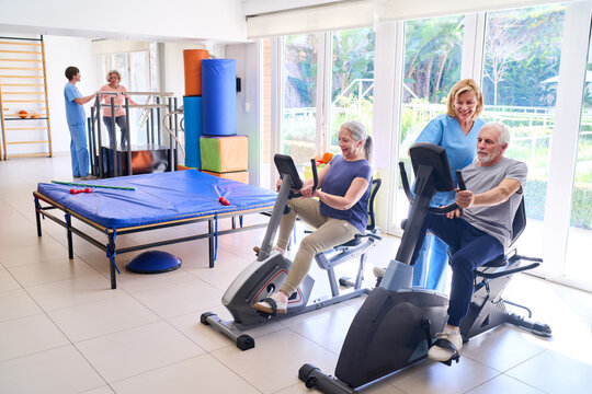 Senior Patients Using Exercise Bikes in Rehab Center with Physiotherapist Assistance for Rehabilitation and Recovery Indoors
