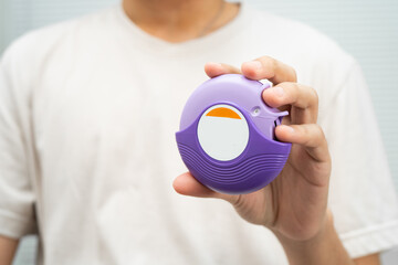 Asthma and chronic obstructive pulmonary disease COPD, Asian young man using metered dose inhaler MDI.