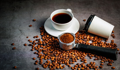 Freshly ground coffee in portafilter with roasted coffee beans and takeaway cup and coffee cup, top view